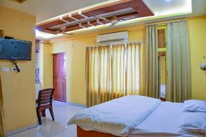 a bedroom with a bed and a chair and a television at Mahadev Mension Tapovan in Rishīkesh