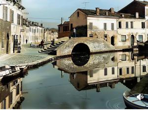 a reflection of a canal in the water with buildings at Salicornia Rooms in Comacchio