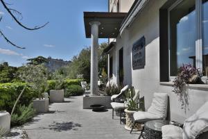 eine Terrasse mit Stühlen und Tischen außerhalb eines Gebäudes in der Unterkunft Hotel Le Corderie in Triest