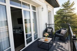 a porch with two chairs and a table with flowers on it at GRAND APARTMENT BALTEZERS in Riga