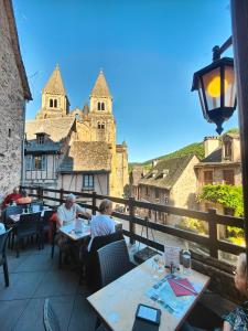 a group of people sitting at tables on a balcony at Auberge Saint Jacques in Conques