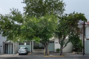 a car parked in a parking lot next to two trees at Casa Othir in Monterrey