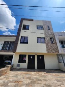 a tall white building with black doors and windows at apartaestudio 304 tranquilo, cómodo y moderno in Tuluá