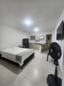 a bedroom with a bed and a kitchen with a fan at apartaestudio 304 tranquilo, cómodo y moderno in Tuluá