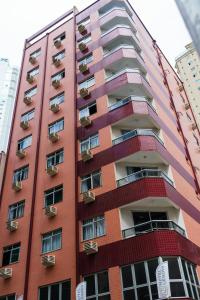 a tall red building with balconies on it at Hotel Gênova BC in Balneário Camboriú
