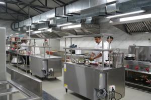 two chefs preparing food in a large kitchen at Winners Hill Resort Walayar by Arcadia in Coimbatore