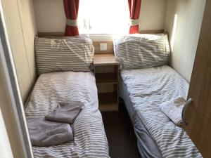 two beds in a small room with a desk at Cosy Costal Escape in Westward Ho