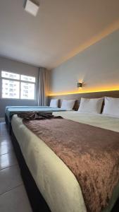 a bedroom with two large beds and a window at Hotel Gênova BC in Balneário Camboriú