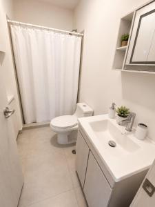 a white bathroom with a toilet and a sink at FIFA Monterrey Stay in Monterrey
