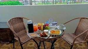 a table with breakfast food on it with two chairs at Pousada Maceió é Massa Beira Mar in Maceió