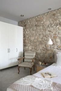 a bedroom with a chair and a stone wall at Accessible Villa Katoi in Angón