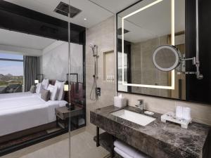 a bathroom with a bed and a sink and a mirror at Swissôtel Clark Philippines in Clark