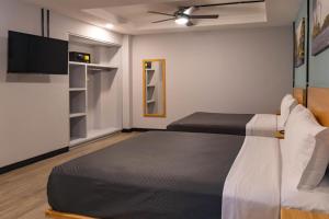 a bedroom with two beds and a flat screen tv at Hotel Escala Centro Histórico in Mexico City