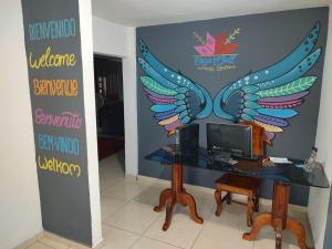 a desk with a computer with wings painted on the wall at Casa Bell in Ciudad Valles