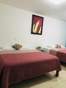 two beds in a hotel room with a picture on the wall at Casa Bell in Ciudad Valles