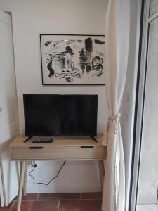a television on a wooden stand in a room at Le petit Riyade in Cambayrac