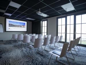 a conference room with white chairs and a projection screen at Ibis Styles Le Touquet in Le Touquet-Paris-Plage