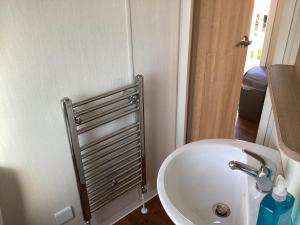 a bathroom with a white sink and a silver radiator at Cosy Costal Escape in Westward Ho +6 photos