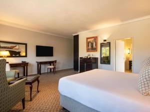 a hotel room with a bed and a desk at Mercure Hotel Windhoek in Windhoek