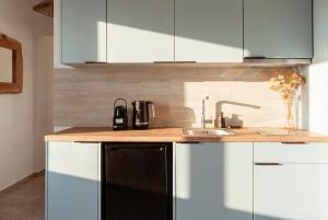 a kitchen with white cabinets and a sink at Kyma Sunset Suite w Prvate Jacuzzi in Paros National Airport