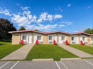 a building with red chairs in a parking lot at Ramada by Wyndham 1000 Islands Gananoque in Gananoque