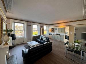 a living room with a black couch and a table at Longsands Beach, Apartment 2, Tynemouth in Tynemouth
