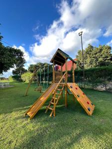 a wooden playground with a slide on the grass at Chalé A-Frame em Garanhuns - PE/ Rota do Frio in Garanhuns