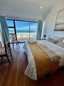 a bedroom with a large bed with a view of the ocean at Skye Beach Villa in Tergniet