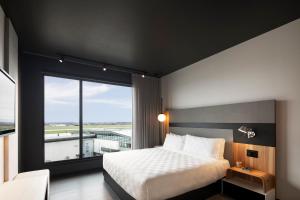 a bedroom with a bed and a large window at Alt Hotel Ottawa Airport in Ottawa