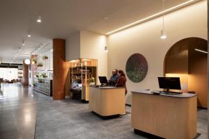 a lobby with two people sitting at a counter with computers at Alt Hotel Ottawa Airport in Ottawa