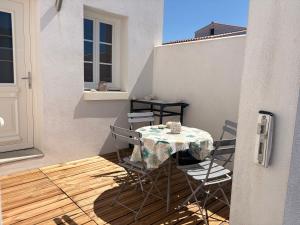a table and chairs on the balcony of a house at Maisonnette Oléron à 30 mètres de la plage 3 étoiles in Saint-Denis-dʼOléron