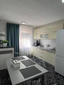 a kitchen with a table with chairs and a refrigerator at Apartament doua camere in Baia Mare