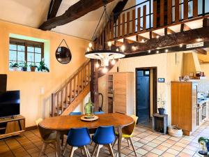 a dining room with a wooden table and blue chairs at Maison paisible Normandie in Saint-Aubin-de-Terregatte