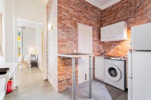 a kitchen with a brick wall and a washer and dryer at Meilleur emplacement de Nice Charming Flat #3 in La Celle-sous-Gouzon