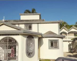a white house with a gate in front of it at C24 guesthouse in Cap-Haïtien