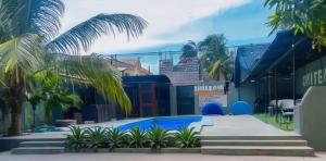 a swimming pool with palm trees in front of a building at C24 guesthouse in Cap-Haïtien