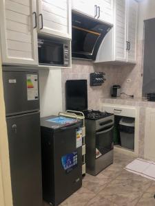 a kitchen with black appliances and white cabinets at Studio 1 chambre in Port-Gentil