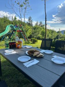 a picnic table with plates of food and a playground at Villa Lux Nature in Sarajevo