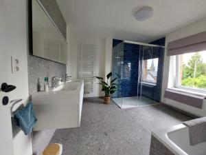 a bathroom with a sink and a glass shower at Ma maison de famille in Saint-Hubert +40 photos