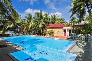 a swimming pool in front of a house with palm trees at Sea Star Resort in Phú Quốc