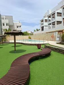 a wooden bench with an umbrella on a green lawn at La casa en la playa in Rota