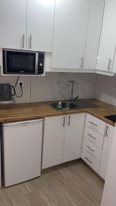 a kitchen with white cabinets and a sink and a microwave at Kostaki spila apartment in Himare
