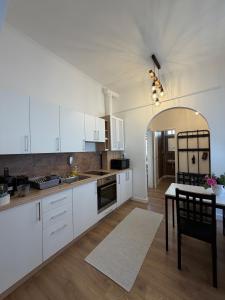 a kitchen with white cabinets and a dining table at Zwinger Apartman in Sopron