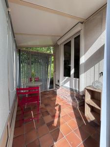 a porch with a red chair and a table at la maisonnette in Nogent-le-Rotrou