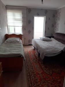 a bedroom with two beds and a rug at Guest House South Wind in Pokrovka