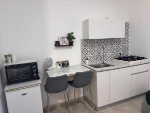 a small kitchen with a counter with two chairs and a microwave at קסם צפתי- סטודיו in Safed