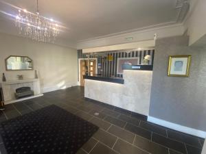 a lobby with a bar with a fireplace and a chandelier at The Durley Chine Hotel in Bournemouth