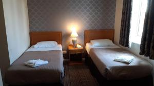 a hotel room with two beds and a lamp on a table at The Durley Chine Hotel in Bournemouth +1 photo