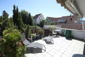 a patio with white chairs and a table at Storchennest - Großzügiges sonniges Wohlfühl-Apartment mit traumhafter Terrasse in Tettnang