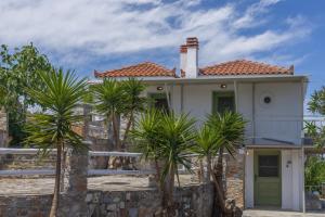 a white house with palm trees in front of it at Vainas Belvedere Villa in Skopelos Town